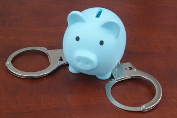 Piggy bank with handcuffs on  table close up. 
