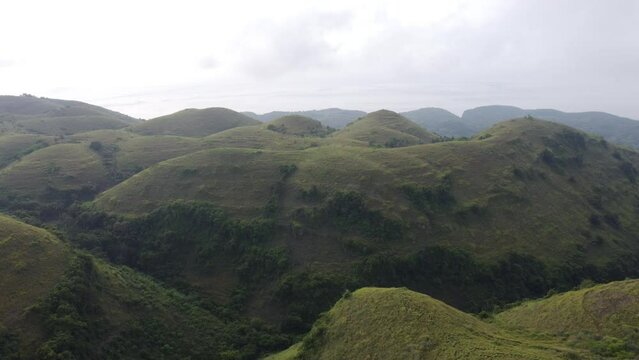flying above exotic looking big rolling Teletubbies Hills in Nusa Penida Island, Bali - Indonesia.
Fertile tropical grassy Farmland Hills and a tourist attraction for its unique geologic cone shape