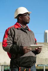 African american worker with tablet computer stands at construction site