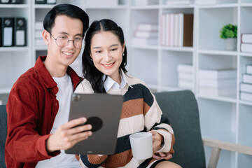 Photo of cute cheerful young couple using laptop and analyzing their finances with documents.