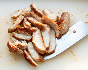 Grilled and sliced chicken breast on white cutting board.