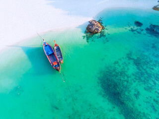 Aerial top view of the  local boat near the lagoon seashore as the tropical island in a coral reef ,blue and turquoise sea  background