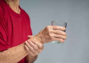 Close-up of hands senior woman trying to hold a glass of water