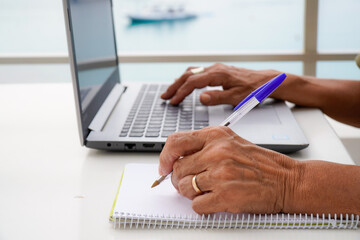 Fototapeta premium left handed unrecognizable woman works with the computer and writes in the notebook outside. international left handers day