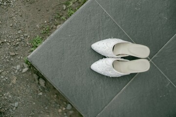 A pair of wedding shoes placed on the terrace of a house, captured from a high angle, creates a stylish and elegant image perfect for capturing the essence of a wedding day