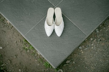 A pair of wedding shoes placed on the terrace of a house, captured from a high angle, creates a stylish and elegant image perfect for capturing the essence of a wedding day