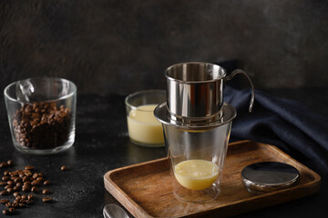 Traditional method of making Vietnamese coffee with sweet condensed milk in glass cup on black background. Close up.