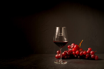 Glass red wine and grapes on black background. - obrazy, fototapety, plakaty