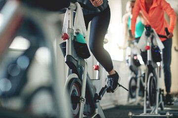 Fitness, legs and exercise bike with people in a gym for a cardio or endurance spinning class...
