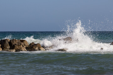 Ola rompiendo en rocas con el horizonte de fondo