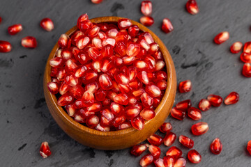 Red ripe pomegranate seeds with lots of juice in a wooden bowl