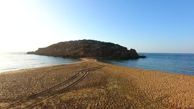 a rock in the middle of the sea with double beach at sunset in oran