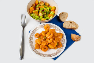 Fried shrimps, fruit-vegetable salad, bread and fork.
