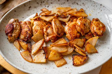 Roasted quail with sliced pear on plate.