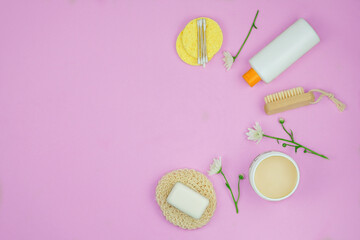Washcloths, shampoo and other accessories in pink background. Copy space for text. Top view.