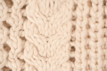 A fragment of beige knitted fabric, knitted from white sheep wool.