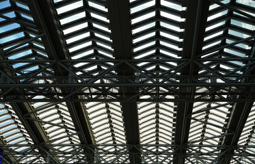 Blue sky seen from the steel frame and glass roof of a building