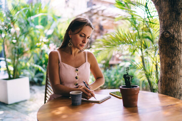 Focused woman taking notes in cafe