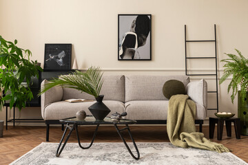 Creative composition of living room interior with mock up poster frame, gray sofa, black coffee table, patterned rug, plants in flowerpots, slippers and personal accessories. Home decor. Template.