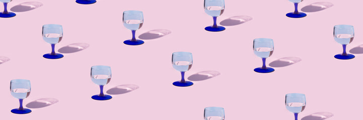 Creative pattern made with wineglass on pink pastel backdrop. Minimal party background. Panoramic header Web banner