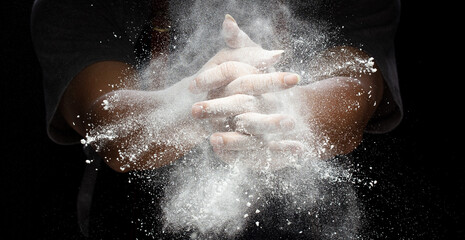 Chef prepare white flour dust for cooking bakery food. Elderly man Chef clap hand, white flour dust explode fly in air. Flour stop motion in air with freeze high speed shutter, black background