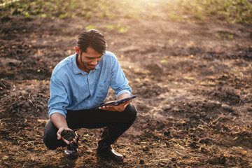 Smart farmer holding soil in his hand and using digital tablet t