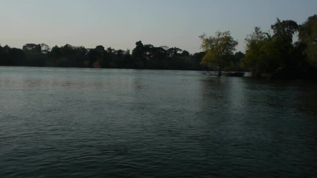View from boat in african river rounding tree covered forest bend enters confluence at dusk