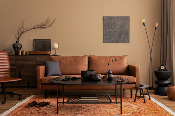 Creative composition of living room interior with mock up poster frame, brown sofa, black coffee table, stylish lamp, vase with branch, patterned rug and personal accessories. Home decor. Template.