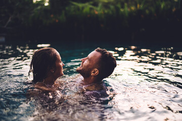 Young man and woman enjoying freedom at nature pool while swimming and bonding togetherness, Caucaisan couple in love feeling happiness during honeymoon vacations in Indonesia - travel and tourism