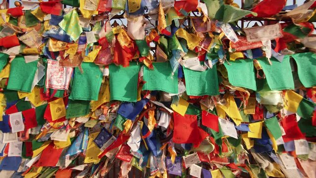 Colored ribbons and small flags with prayer flutter in wind on gates adorned with buddhist symbols