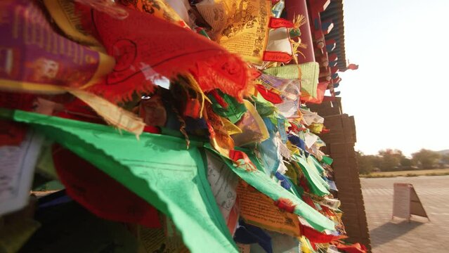Multi-colored ribbons and small flags with prayers are tied to the gates of buddhist temple