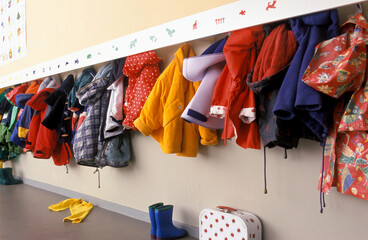 Coat rack in a nursery with a lot of children coats on a rack  - obrazy, fototapety, plakaty