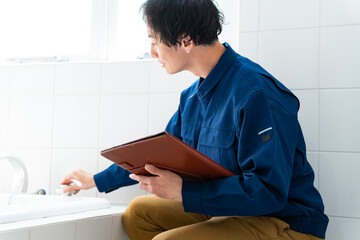風呂場をチェックする作業着を着た日本人男性