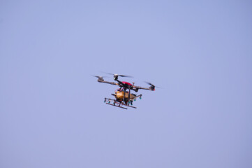 Fototapeta na wymiar agricultural drone Spraying fertilizers or agricultural chemicals flying in the sky.
