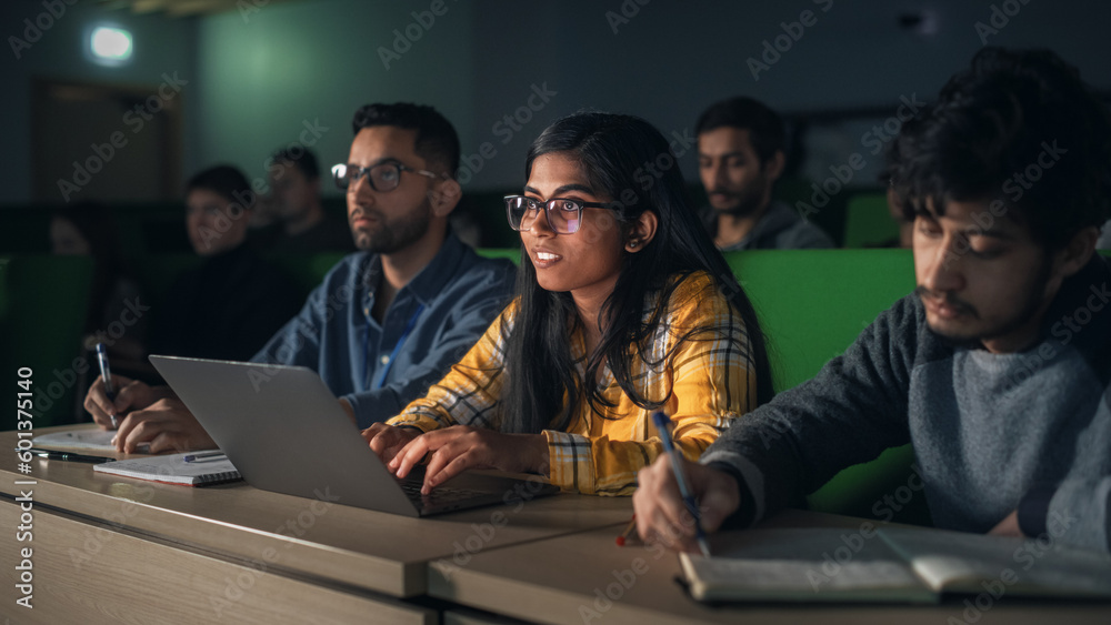 Poster Close Up Portrait of a Smart Beautiful Indian Female Student Studying in University with Diverse Multiethnic Classmates. Young Woman Using Laptop Computer and Taking Notes During the Lecture