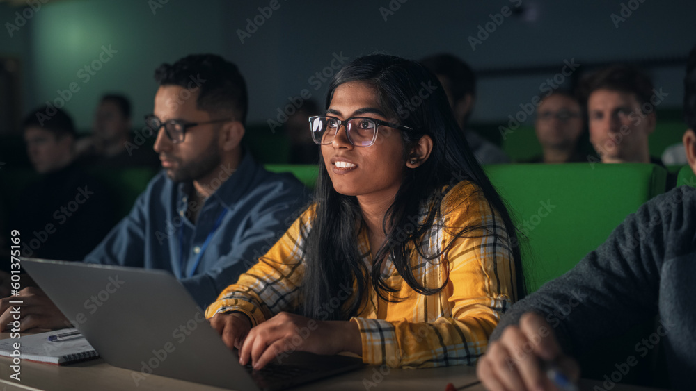 Poster Portrait of a Smart Talented Indian Female Student Studying in University with Diverse Multiethnic Classmates. Young Woman Using Laptop Computer and Taking Notes During the Lecture
