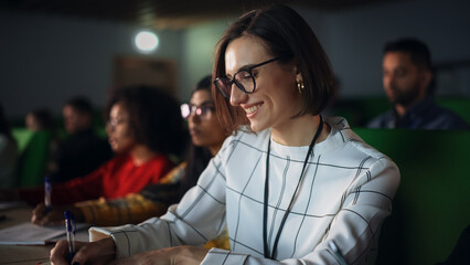 Portrait of a Happy Smart Female Student, Studying in University with Diverse Multicultural Colleagues. She is Writing Down a Summary from the Lecture in Her Notebook