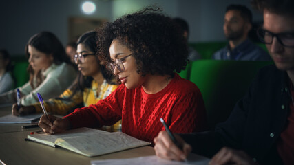 Talented Smart Multiethnic Hispanic Female Student Studying in College with Diverse Colleagues. Black Young Woman Writing Down a Summary from the Lecture in Her Notebook - obrazy, fototapety, plakaty
