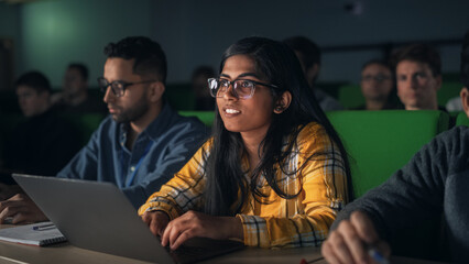 Portrait of a Smart Talented Indian Female Student Studying in University with Diverse Multiethnic Classmates. Young Woman Using Laptop Computer and Taking Notes During the Lecture - obrazy, fototapety, plakaty