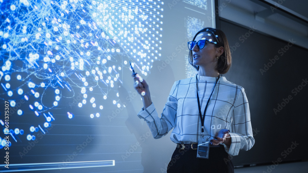 Poster Young University Professor Explaining a Web Development Project to a Group of Students in a Dark Auditorium. Female Teacher Showing a Back-End Programmers Code on a Big Projector Screen