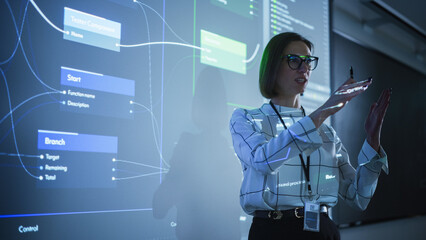 Young Businesswoman Presenting a Web Development Road-Map in a Dark Room with Projecting Images....