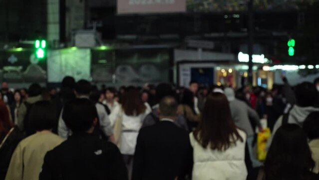 SHIBUYA, TOKYO, JAPAN - APRIL 2023 : Back shot and crowd of people at SHIBUYA SCRAMBLE CROSSING. Japanese people, urban city life, travel and tourism concept video in 4K. Slow motion shot at night.