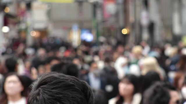 SHIBUYA, TOKYO, JAPAN - APRIL 2023 : Back shot and crowd of people at SHIBUYA SCRAMBLE CROSSING. Japanese people, urban city life, travel and tourism concept video in 4K. Shot in daytime.