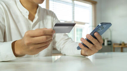 Closed up and focus on hand of man holding credit card and using smartphone. Shopping online, e-commerce, internet banking.