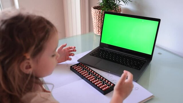 A girl from the back is engaged in mental arithmetic on the abacus online on a laptop, chroma key background. The concept of teaching children to count quickly, Russian mathematics. 