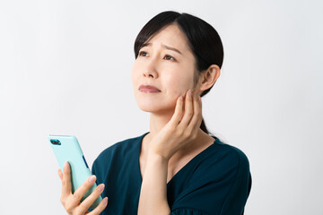 スマートフォンを持ちながらネガティブな表情をする若い女性
