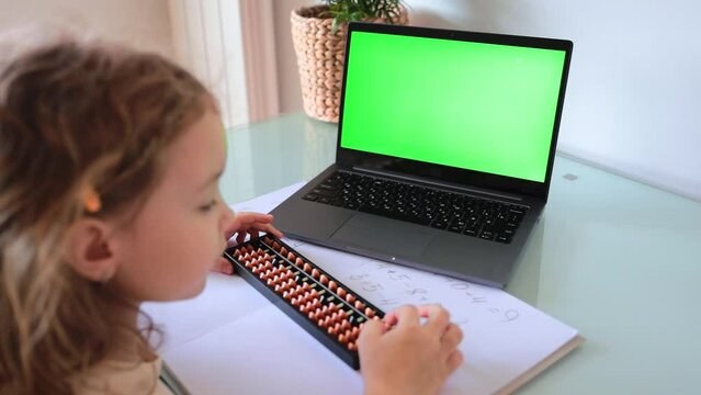 A girl from the back is engaged in mental arithmetic on the abacus online on a laptop, chroma key background. The concept of teaching children to count quickly, Russian mathematics. 
