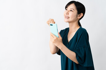 スマートフォンを持ちながらガッツポーズをする若い女性