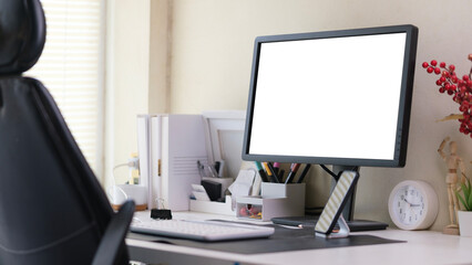 Home office interior with blank computer monitor and office supplies on white table.