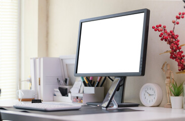 Blank computer monitor and office supplies on white table in modern workplace.